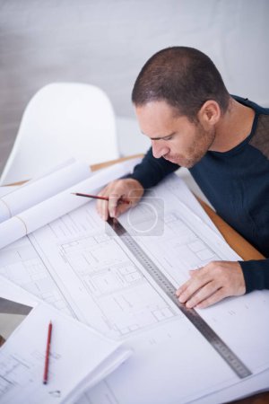 Photo for Checking his work to ensure the highest standard. High angle shot of an architect drafting up building plans - Royalty Free Image