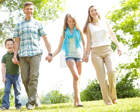 Téléchargez les photos : Balades estivales en famille. Une jeune famille heureuse se promène dans le parc par une journée d'été - en image libre de droit