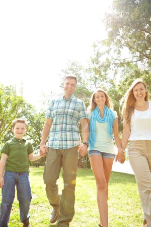 Téléchargez les photos : Profiter d'une promenade en famille. Une jeune famille heureuse se promène dans le parc par une journée d'été - en image libre de droit