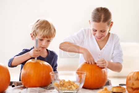 Photo for Brother and sister bonding. A brother and sister hollowing and carving pumpkins for halloween - Royalty Free Image