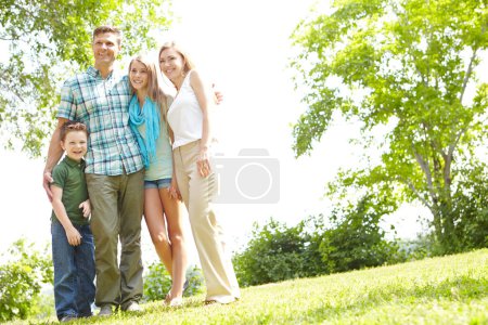 Téléchargez les photos : Des moments en famille dans le parc. Une famille heureuse debout ensemble dans le parc un jour d'été - en image libre de droit