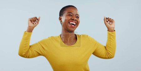 Foto de Mujer negra emocionada, bailando y celebrando por ganar o ascender contra un fondo gris de estudio. Rostro de mujer africana feliz persona o modelo en la alegría o la satisfacción de bono o buenas noticias. - Imagen libre de derechos