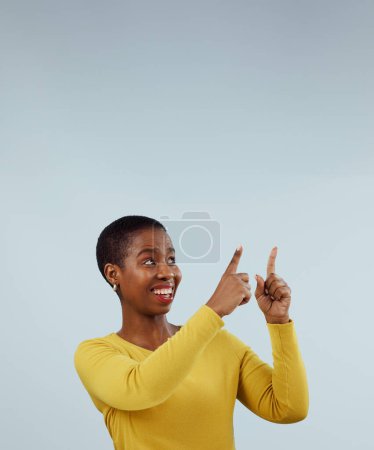 Foto de Burla, sonrisa y mujer negra con la mano apuntando hacia arriba en el estudio para la presentación sobre fondo gris. Noticias, anuncio y modelo femenino africano muestran retroalimentación, lista de verificación o calendario, promoción o plataforma. - Imagen libre de derechos