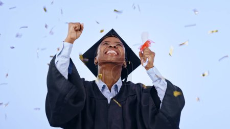 Téléchargez les photos : Diplômée, étudiante et célébration des confettis, succès et réussite du collège ou de l'université en studio. Diplômé africain excité avec prix, diplôme et oui pour l'éducation sur un fond bleu. - en image libre de droit