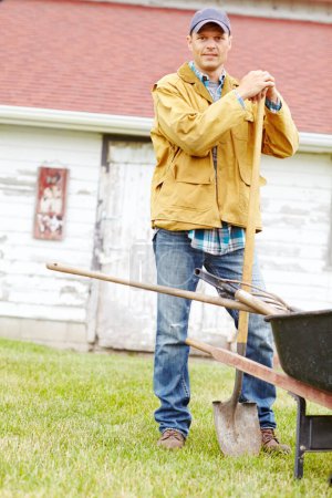 Foto de Casi es hora de empezar a cavar. Retrato de un hombre feliz parado junto a una carretilla con una pala en la mano - Imagen libre de derechos