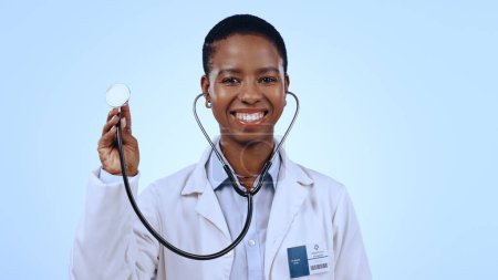 Foto de Mujer feliz, médico y estetoscopio para la atención médica en estudio de fondo azul para maqueta en medicina. Retrato, persona negra y profesional médico con sonrisa para el bienestar, los pulmones y la respiración. - Imagen libre de derechos