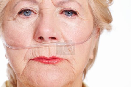 Foto de La enfermedad cobra su precio... ¿estás cubierto por la eventualidad? Una anciana enferma que lleva una cánula nasal para oxígeno aislado en blanco - Macro Primer plano - Imagen libre de derechos