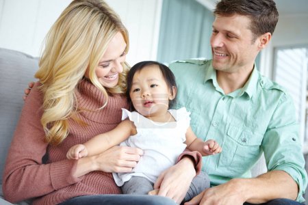 Photo for Youre too cute, arent you. A happy couple spending time with their beautiful adopted daughter while at home - Royalty Free Image