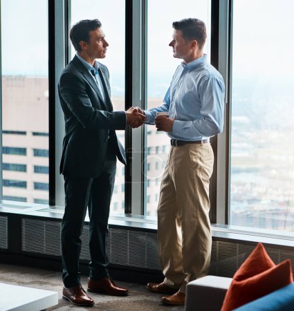 Foto de Listo para hacer negocios. dos hombres de negocios estrechando la mano en una oficina corporativa - Imagen libre de derechos