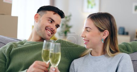 Photo for Couple, new home and toast champagne on sofa for celebration with boxes in living room together. Man, woman and wine glass with cheers, achievement and investment in real estate, property or house. - Royalty Free Image