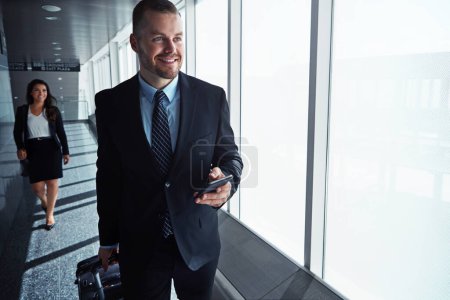 Photo for Business man, woman and phone by airport window for vision, thinking and contact in corridor with smile. Entrepreneur, suitcase and smartphone with flight schedule for global immigration in London. - Royalty Free Image