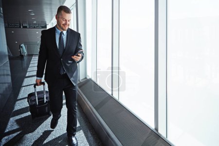 Photo for Business man, phone and texting in airport for smile, luggage or email notification on international travel. Entrepreneur, bag or smartphone for flight schedule, global immigration or idea in London. - Royalty Free Image
