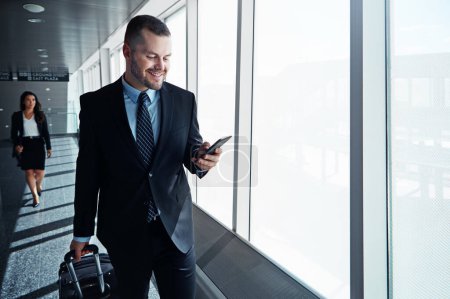 Photo for Business man, phone and travel in airport window for reading, thinking and contact in corridor with smile. Entrepreneur, luggage and smartphone for flight schedule and global immigration in London. - Royalty Free Image