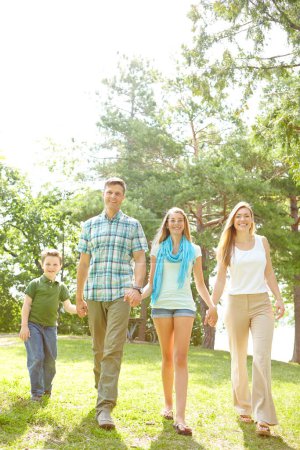 Photo for Strolling through the park. A happy young family walking through the park together on a summers day - Royalty Free Image
