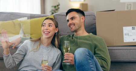Photo for Happy couple, celebration and champagne for moving home or new property, drink in living room. Man, woman and wine glass for achievement in apartment boxes for change or floor chat, cheers at sofa. - Royalty Free Image