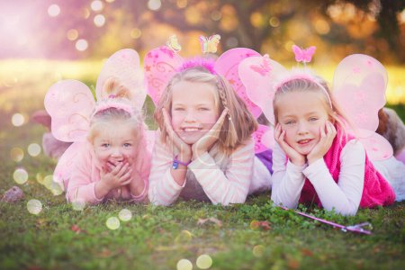 Téléchargez les photos : Rendre leur enfance encore plus magique. Portrait de trois petites sœurs déguisées en fées et s'amusant à l'extérieur - en image libre de droit