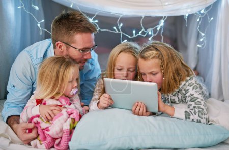 Photo for Hes there to ensure safe online browsing. a father and his daughters using a digital tablet before bedtime - Royalty Free Image