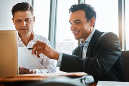 Foto de Estos son realmente impresionantes. dos hombres de negocios que tienen una discusión mientras están sentados junto a una computadora portátil - Imagen libre de derechos