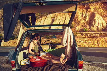 Photo for Im just doing my thing. a young woman relaxing in the back of her car on a roadtrip - Royalty Free Image