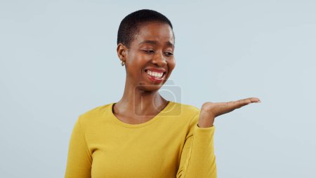 Photo for Happy black woman, smile and palm for advertising or marketing against a studio background. Face of African female person with hand out showing advertisement, platform or presentation on mockup space. - Royalty Free Image