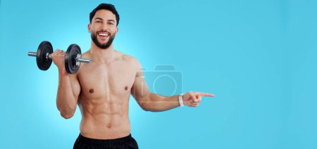 Photo for Gym, portrait and happy man with dumbbell or hand pointing to studio for fitness, promo or info on blue background. Face, smile and male bodybuilder show sign up, presentation or membership offer. - Royalty Free Image