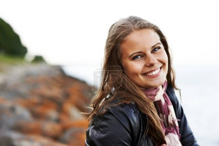 Photo for Portrait, happy woman and smile on face for outside, trip or travel on holiday to coastline. Young person, excited emoji or expression with trendy, style and fashion on vacation, nature and Ireland. - Royalty Free Image