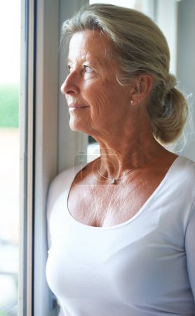 Photo for Senior, woman and thinking of nostalgia in home with smile for fond memory, peace or happiness. Elderly person, looking and window with relaxed expression on face for wellness, care and retirement. - Royalty Free Image