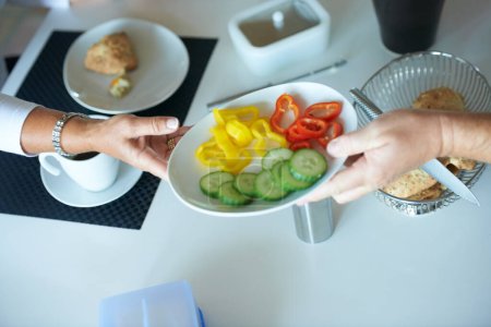 Photo for People, hands and passing salad at breakfast table for vegetables, diet or healthy eating at home. Closeup of person giving plate of natural organic food for nutrition snack or meal together at house. - Royalty Free Image