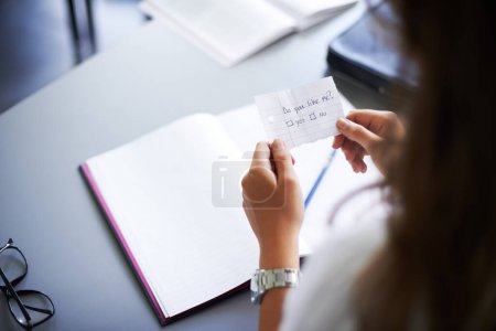 Photo for Secret, note and student with love letter in class at high school with girl and social communication. Hand, paper and teenager with checklist, information or romantic question in classroom from crush. - Royalty Free Image