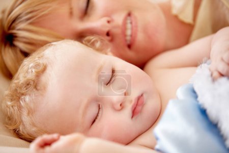 Téléchargez les photos : Dormir, maman et bébé calme au lit ainsi que la paix, le bonheur et l'amour pour le bébé dans la sieste du matin. Mère, câlin et dormir avec l'enfant en gros plan et se reposer avec un sourire dans la chambre ou la maison familiale. - en image libre de droit