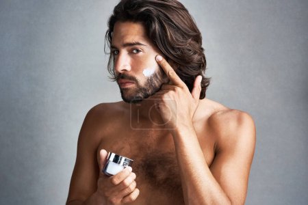 Photo for Portrait, skincare or lotion with the face of a man in studio on a gray background for his grooming routine. Beauty, facial and a handsome or shirtless young person with antiaging cream for his skin. - Royalty Free Image