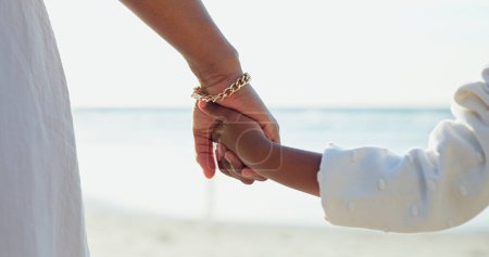 Téléchargez les photos : Femme, enfant ou tenir la main pour l'amour par la plage ou coller ensemble pour le bonheur pendant les vacances d'été. Engagement, mère ou enfant dans une relation de soutien, vacances ou détente bien-être par océan calme. - en image libre de droit