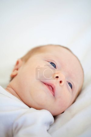 Téléchargez les photos : Gros plan, bébé et visage pour se réveiller au lit après un bon rêve, dormir ou faire une sieste dans la crèche. Bébé, regarder et se détendre sur l'oreiller pour la croissance de l'enfant, cognitif et le développement dans l'espoir d'une étape importante de l'avenir. - en image libre de droit