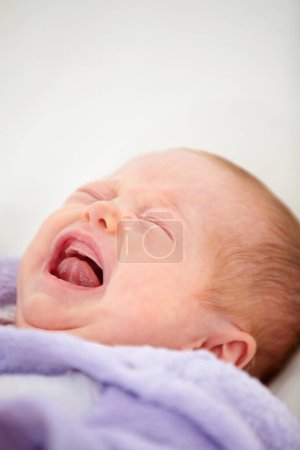 Photo for Sad, crying or tantrum with a baby on a bed closeup in a home for emotion, expression or child development. Face, tired or hungry with a newborn infant in the bedroom of an apartment for growth. - Royalty Free Image