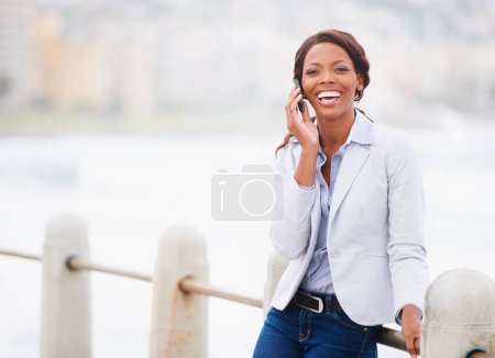 Photo for Business woman, phone call and ocean in portrait, smile and contact for networking, negotiation or chat. African entrepreneur, smartphone and sea promenade with talk, happy and walking in Cape Town. - Royalty Free Image