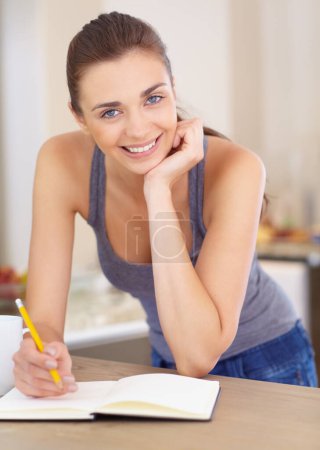 Photo for Portrait, smile and woman writing in a notebook while in the kitchen of her home in the morning. Planning, journal or diary and a happy young writer in her apartment with a creative idea for a story. - Royalty Free Image