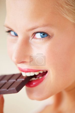 Photo for Portrait, eating or happy woman bite chocolate bar, snack or junk food for wellness, stress relief or craving. Face headshot, delight or girl taste cacao slab, antioxidant benefits or diet cheat meal. - Royalty Free Image