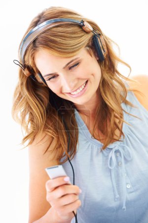 Photo for Woman, headphones and music device in studio for online streaming, listening or radio playlist. Female person, white background and audio hear for album happy or dancing electronics, track for relax. - Royalty Free Image