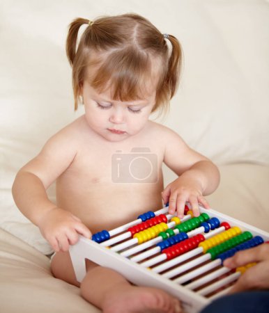 Photo for Learning, child development and a girl baby with an abacus in the bedroom of a home for growth. Kids, education or math with an adorable and curious young toddler counting on a bed in an apartment. - Royalty Free Image