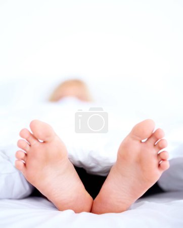 Photo for Home, closeup and person with feet, bed and relax in the morning, sleeping and weekend break with linen. Human, apartment and foot with bedroom, comfort or dreaming with blanket, resting or mattress. - Royalty Free Image