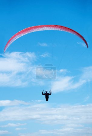 Photo for Person, parachute and paragliding in blue sky in air, nature for exercise with healthy adventure for extreme sport. Athlete, flight or fearless by outdoor fitness for wellness, helmet or safety gear. - Royalty Free Image