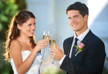 Téléchargez les photos : Joyeux couple, mariage et acclamations avec champagne pour célébrer le mariage, l'amour ou l'engagement. Un homme et une femme mariés sourient avec des verres d'alcool pour un toast, une date ou une lune de miel lors d'une cérémonie en plein air. - en image libre de droit