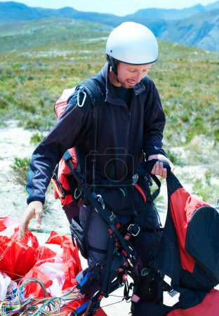 Photo for Sports, parachute and man in nature with equipment, safety preparation and helmet in paragliding exercise. Athlete, training or gear for outdoor adventure, backpack or happy wellness in countryside. - Royalty Free Image