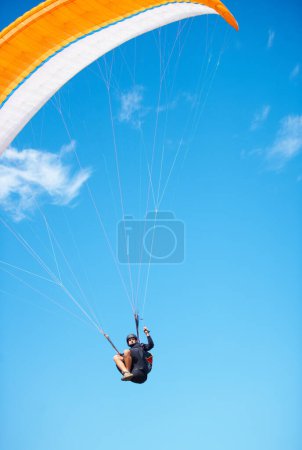 Photo for Man, paragliding and blue sky adventure fun in clouds for explore city, outdoor courage or fearless athlete. Male person, parachute and mockup space or safety equipment for landing, flying in nature. - Royalty Free Image