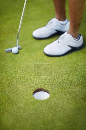 Photo for Sports, golf hole and shoes of golfer on course playing game, practice and training for competition. Recreation, grass and closeup of person by tee, ball and golfing club for winning stroke or score. - Royalty Free Image