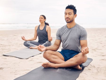 Foto de Pareja de amigos, pose de loto y meditación en la playa para el fitness zen, ejercicio tranquilo y mindfulness o bienestar holístico. Jóvenes en meditación, yoga por mar y océano o naturaleza para la salud mental. - Imagen libre de derechos