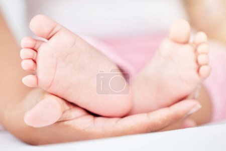 Téléchargez les photos : Famille, soins et les pieds d'un bébé dans les mains d'un parent gros plan dans la chambre de leur maison ensemble. Enfants, amour ou bien-être et un bébé sur un lit dans un appartement avec une personne adulte. - en image libre de droit