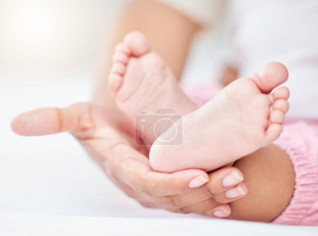 Téléchargez les photos : Famille, amour et les pieds d'un bébé dans les mains d'un parent gros plan dans la chambre de leur maison ensemble. Enfants, soins ou bien-être et un bébé sur un lit dans un appartement avec une personne adulte. - en image libre de droit