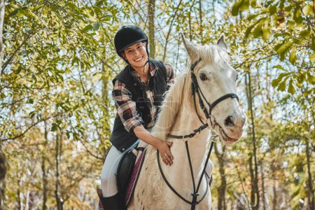 Téléchargez les photos : Portrait de femme heureuse à cheval, chevauchant en forêt et pratiquant pour la compétition, la course ou le dressage avec des arbres. Sport équestre, jockey ou cavalier sur animal dans les bois pour l'aventure, l'entraînement et les soins - en image libre de droit
