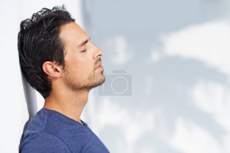 Photo for Thinking, calm and man profile by a white wall outdoor in the sun with freedom and ideas. Relax, peace and male person with mockup and summer with vitamin D, leaning and contemplating with outfit. - Royalty Free Image